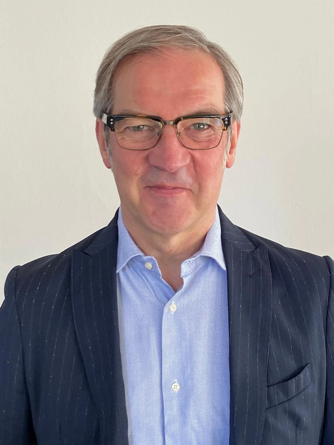 Wendelin Mueller Consultants - Unternehmenstransformation und Beratung - Aufnahme aus der Froschperspektive, die zu mehreren dunklen, modernen Wolkenkratzern vor einem bewölkten Himmel hinaufblickt.